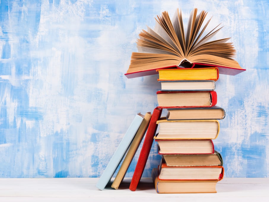 Stack of colorful hardback books, open book on blue background